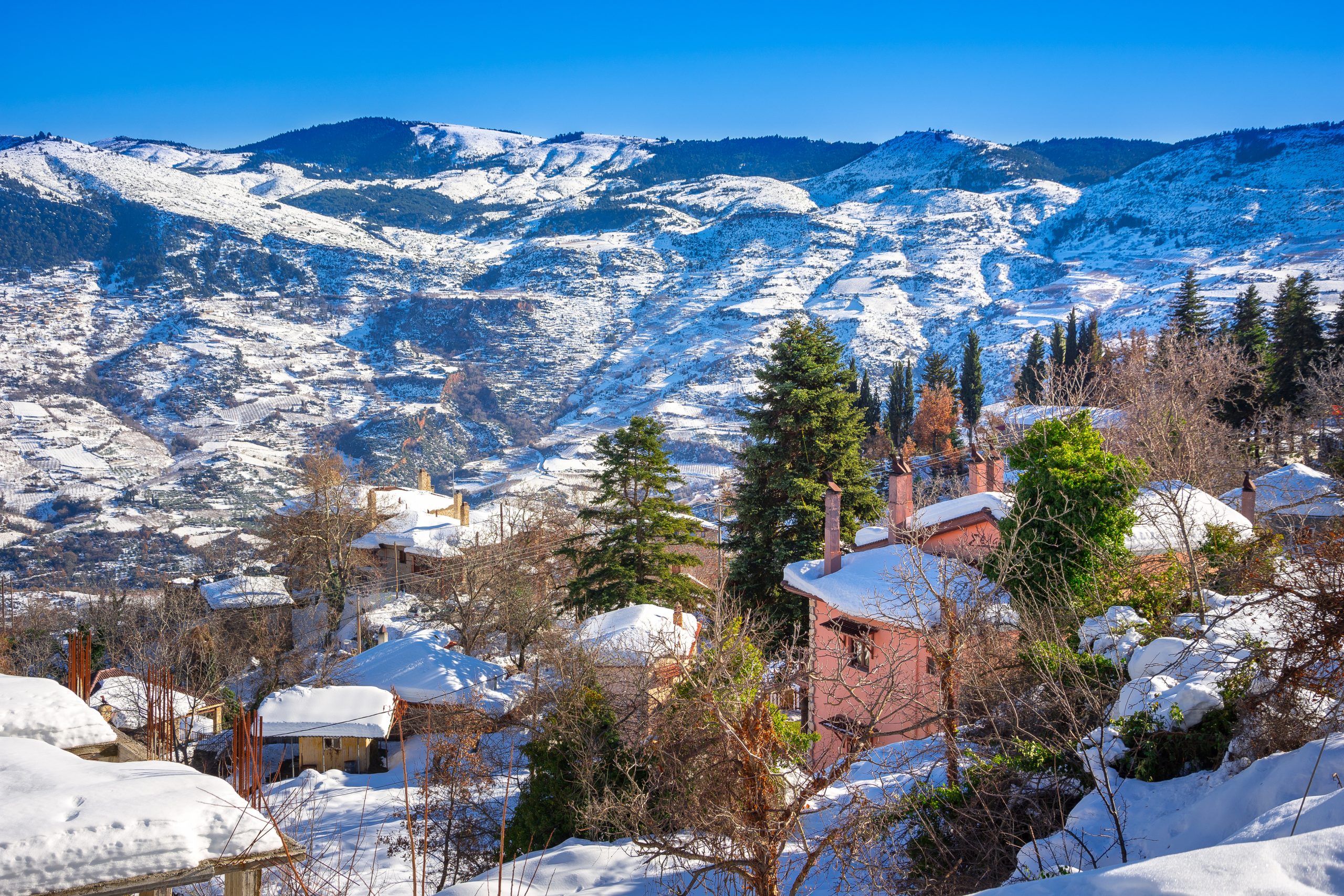 Winter landscape with snow, wooden houses and clear blue sky, Trikala Korinthias, Greece.