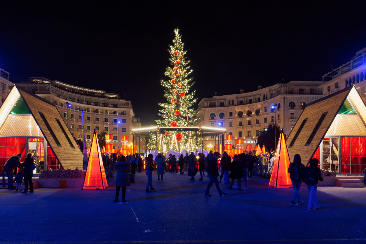 Night view of festive installments at southern part of main city square, with crowd.