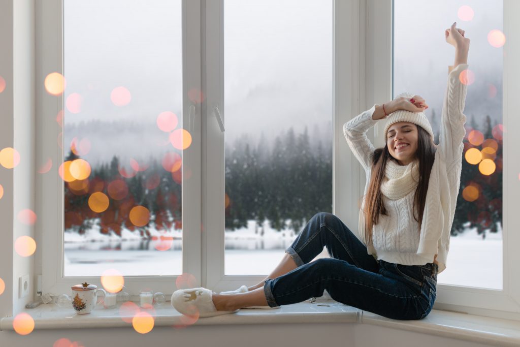 woman sitting at window in winter christmas house