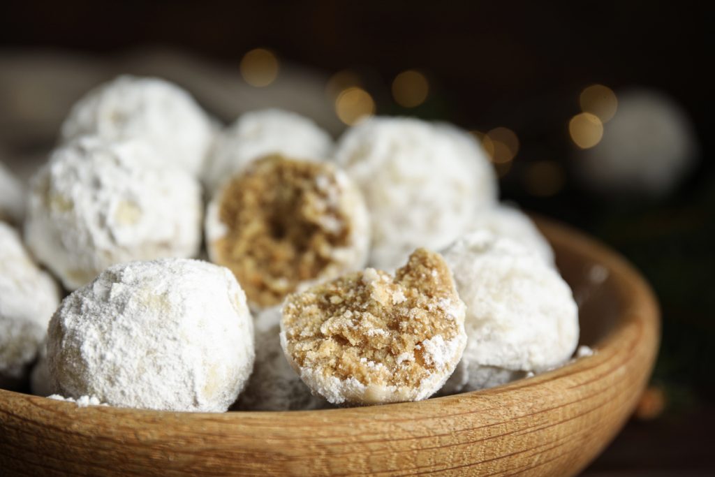 Tasty snowball cookies in wooden bowl, closeup. Christmas treat