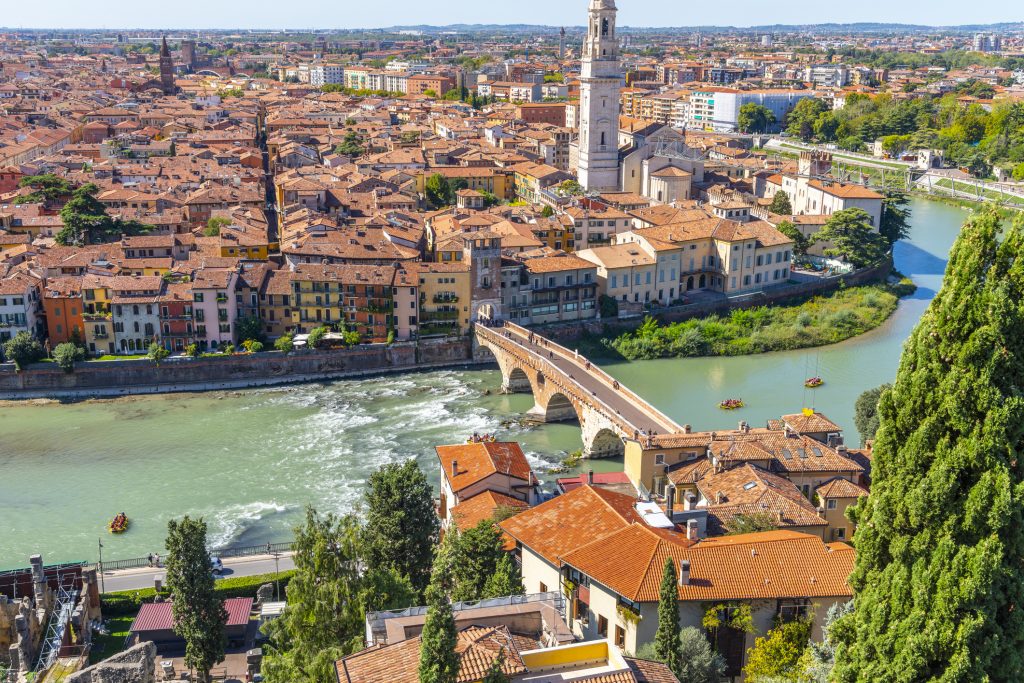 View of the historic center of the city of Verona, Italy and the Ponte Pietra bridge and river Adige from the hillside fortress of Castel San Pietro, with groups of rafters enjoying a ride on the river.